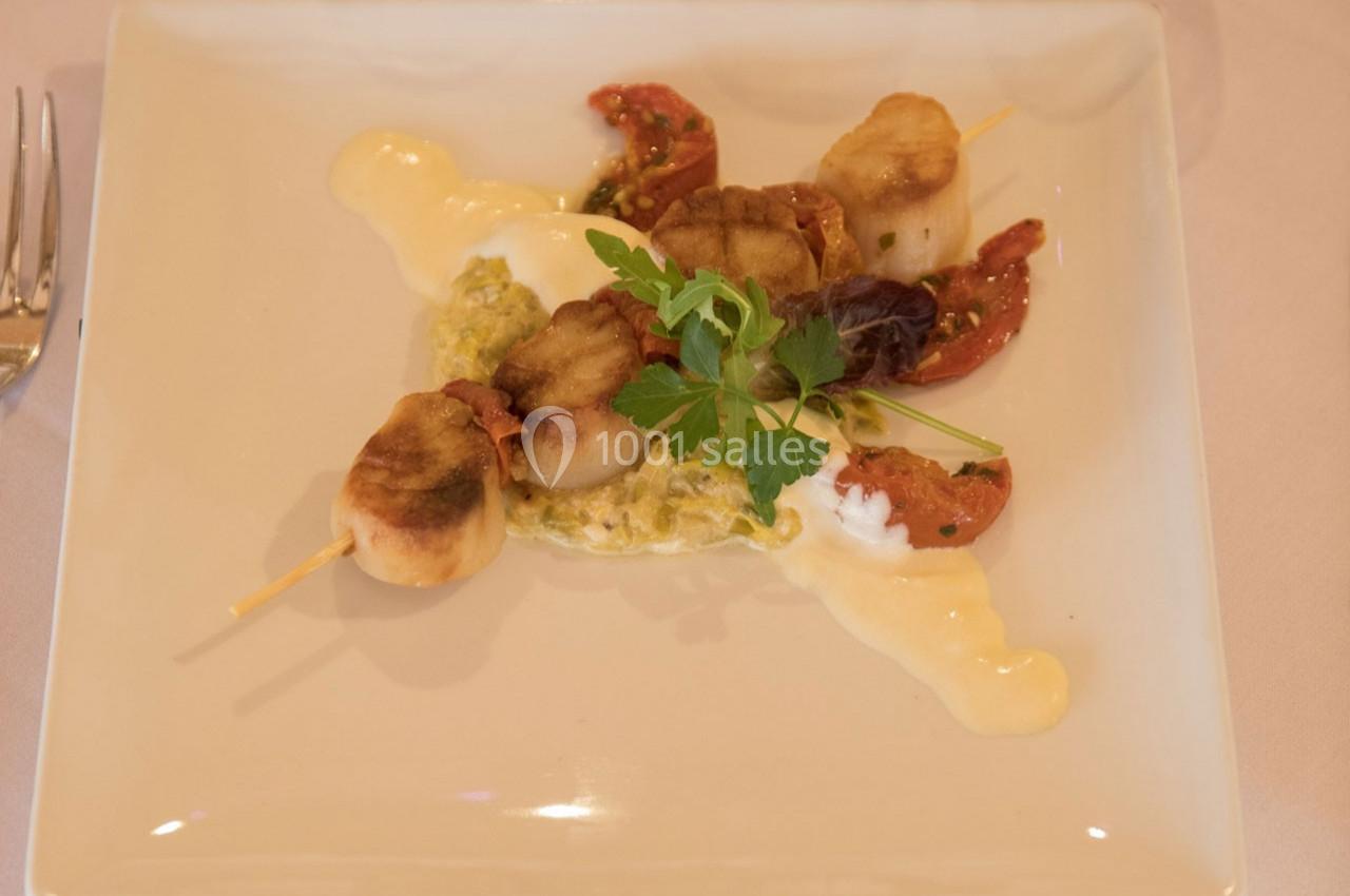 Brochette de noix de Saint-Jacques grillées servie avec une sauce crémeuse, tomates séchées et herbes fraîches.