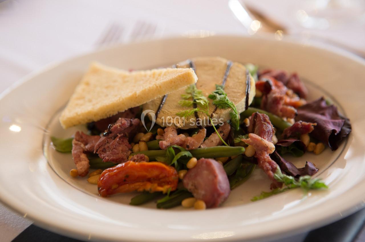 Assiette de salade composée avec haricots verts, lardons, tomates séchées, fromage grillé et triangles de pain.