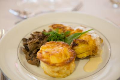 Assiette contenant une mousse verte garnie de persil, accompagnée de tomates rôties et de points de sauce balsamique.