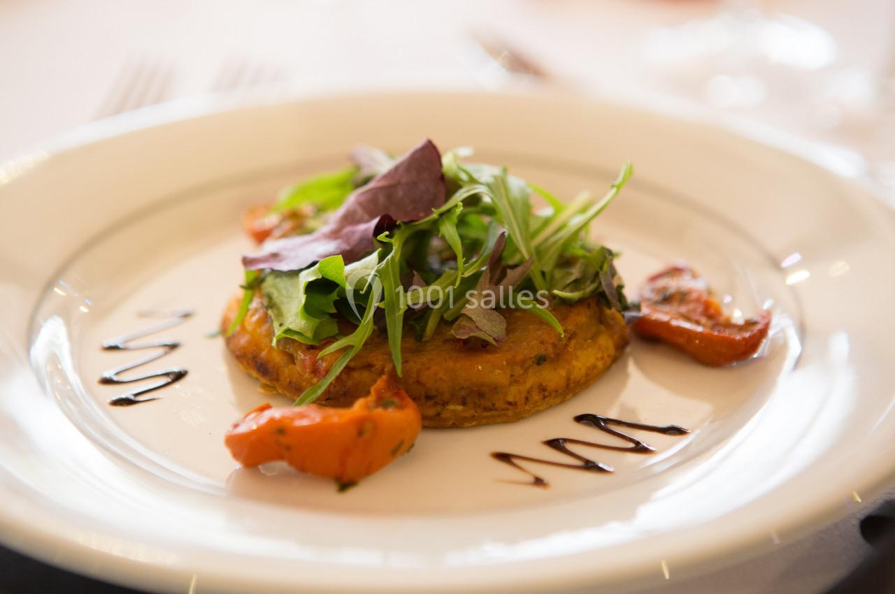 Assiette contenant une tartelette garnie de légumes grillés, de salade verte et décorée de traits de sauce balsamique.