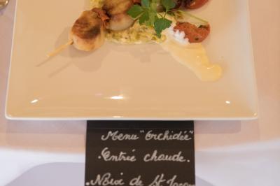 Assiette contenant une mousse verte garnie de persil, accompagnée de tomates rôties et de points de sauce balsamique.