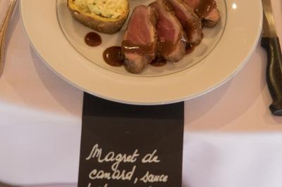 Assiette contenant une mousse verte garnie de persil, accompagnée de tomates rôties et de points de sauce balsamique.