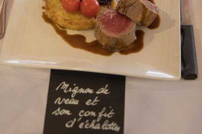 Assiette contenant une mousse verte garnie de persil, accompagnée de tomates rôties et de points de sauce balsamique.