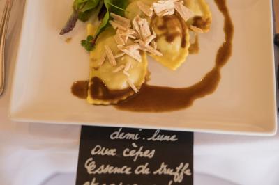 Assiette contenant une mousse verte garnie de persil, accompagnée de tomates rôties et de points de sauce balsamique.