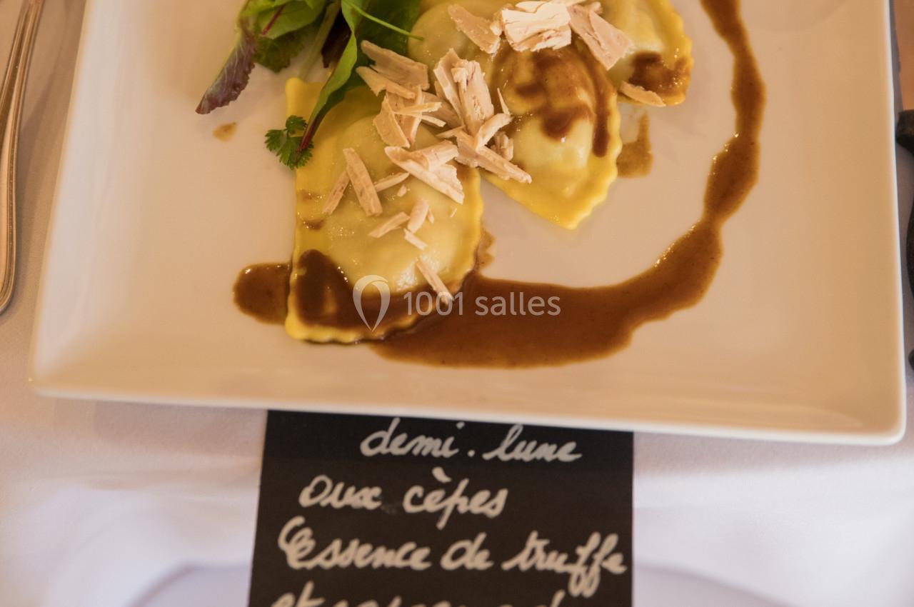 Assiette de ravioles garnies de cèpes, nappées de sauce, décorées de copeaux de foie gras et accompagnées de salade verte.