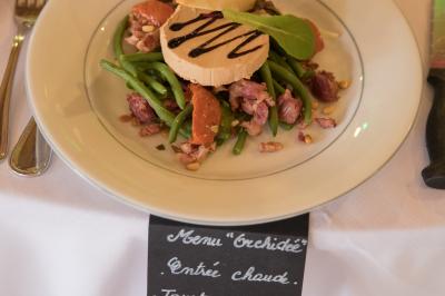 Assiette contenant une mousse verte garnie de persil, accompagnée de tomates rôties et de points de sauce balsamique.