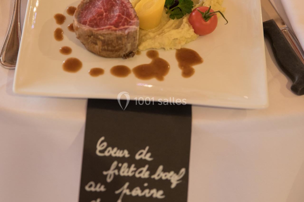 Assiette gastronomique avec filet de bœuf, légumes colorés, purée et sauce, présentée sur une table dressée.