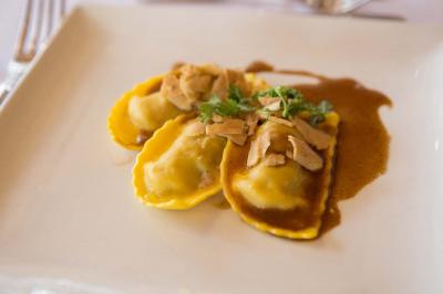 Assiette contenant une mousse verte garnie de persil, accompagnée de tomates rôties et de points de sauce balsamique.