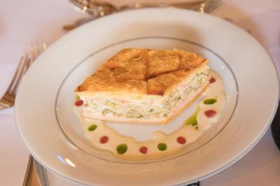 Assiette contenant une mousse verte garnie de persil, accompagnée de tomates rôties et de points de sauce balsamique.