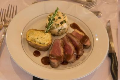 Assiette contenant une mousse verte garnie de persil, accompagnée de tomates rôties et de points de sauce balsamique.