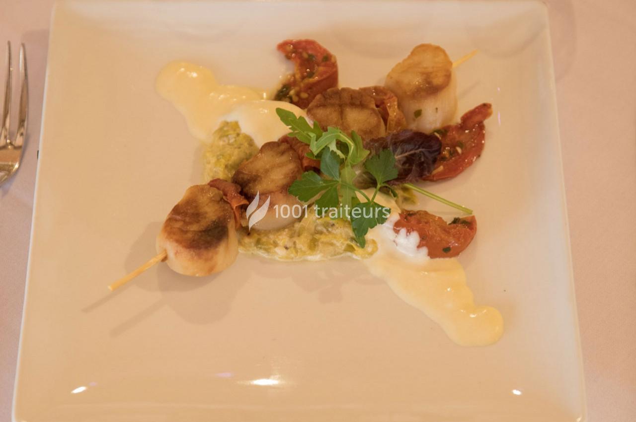 Brochette de noix de Saint-Jacques grillées servie avec une sauce crémeuse, tomates séchées et garniture verte.