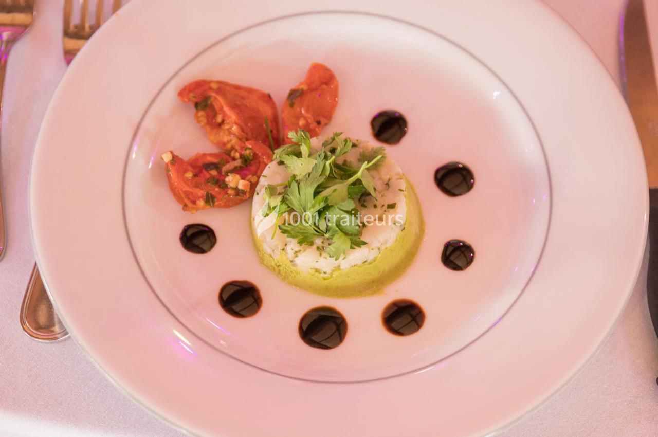 Assiette contenant une mousse verte garnie de persil, accompagnée de tomates rôties et de points de sauce balsamique.
