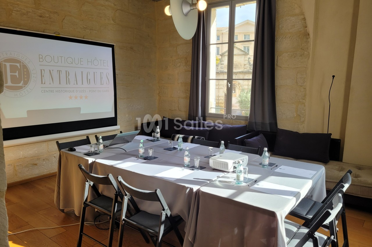 Salle de réunion lumineuse avec table rectangulaire, chaises pliantes, matériel de présentation et fenêtre donnant sur l…