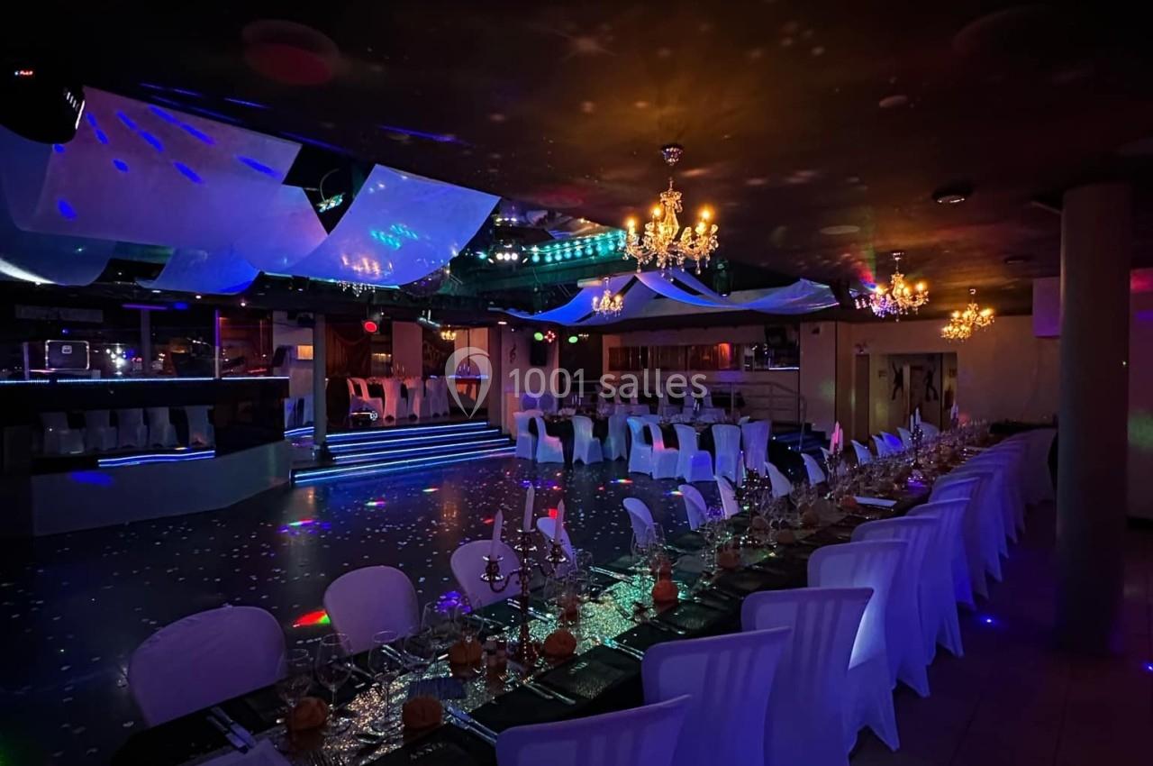 Salle de réception décorée avec des tables dressées, éclairage tamisé et ambiance festive.