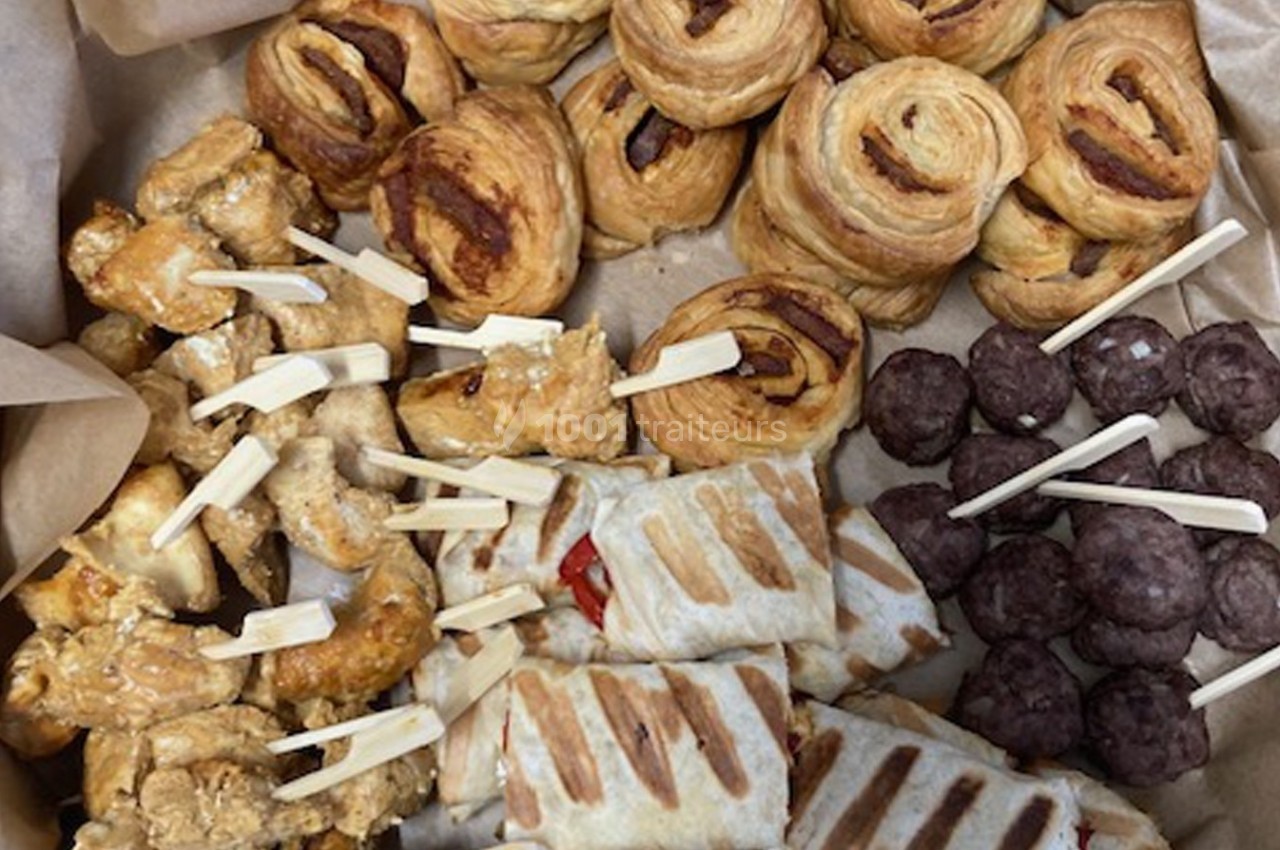 Assortiment de bouchées salées comprenant feuilletés, brochettes de poulet, boulettes de viande et wraps grillés.
