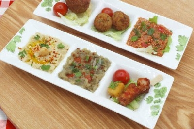 Miniature Traiteur Saint-Denis (Seine-Saint-Denis) - Leon Catering Libanais  #14 Assiette de wraps garnis autour d'un bol de sauce blanche, accompagnée de légumes marinés et de tranches de tomate.