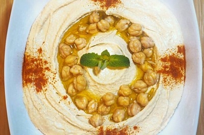 Assiette noire contenant des wraps garnis, accompagnée de légumes, de tranches de tomate et d'une sauce blanche au centre.