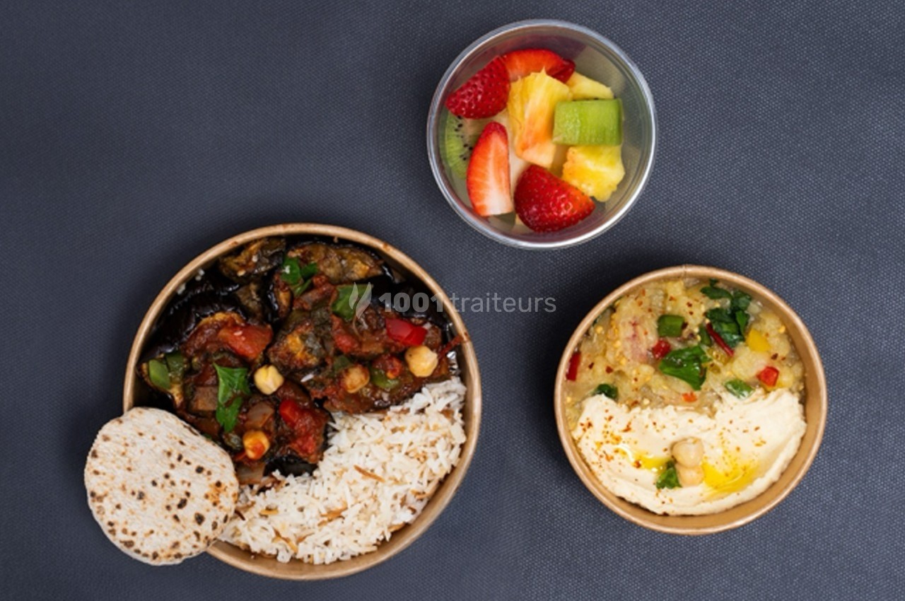Assiette avec riz, légumes sautés, galette, houmous, purée de pois chiches et bol de fruits frais.