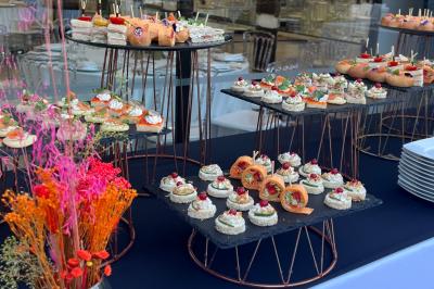 Entrée d'un bâtiment blanc entouré d'arbres, avec des portes vitrées illuminées par une lumière intérieure.