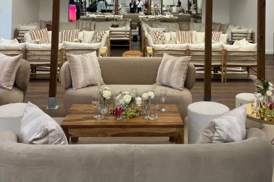 Entrée d'un bâtiment blanc entouré d'arbres, avec des portes vitrées illuminées par une lumière intérieure.