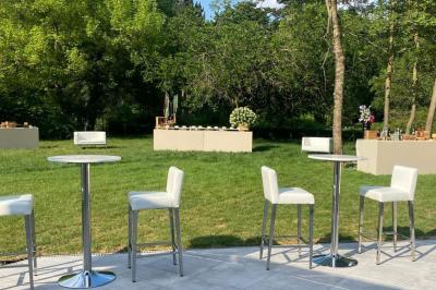 Entrée d'un bâtiment blanc entouré d'arbres, avec des portes vitrées illuminées par une lumière intérieure.
