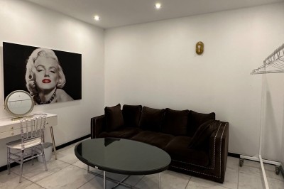 Entrée d'un bâtiment blanc entouré d'arbres, avec des portes vitrées illuminées par une lumière intérieure.