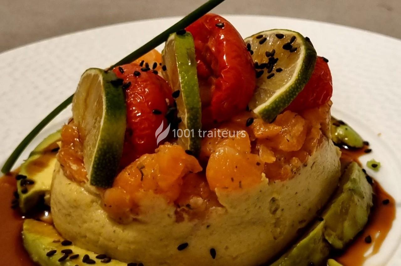 Assiette garnie d'une mousse verte, saumon mariné, tomates cerises, rondelles de citron vert et graines noires.