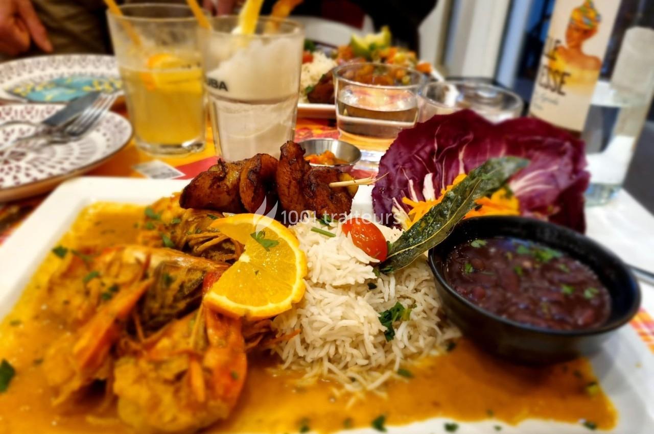 Assiette de crevettes en sauce avec riz, légumes, crudités et accompagnements, servie sur une table dressée.