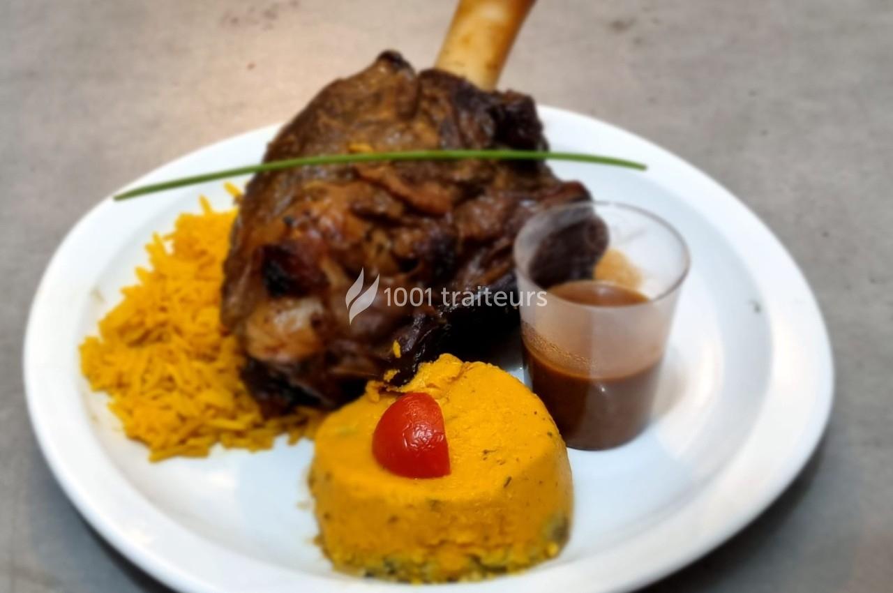 Jarret d'agneau rôti servi avec riz safrané, purée de légumes, sauce en verrine et décoration de ciboulette.