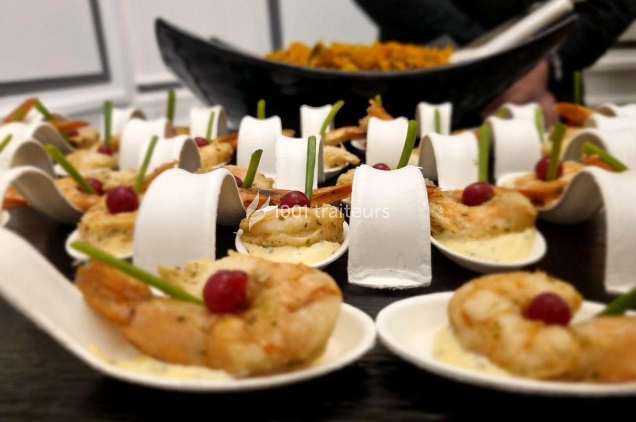 Crevettes servies sur des cuillères individuelles avec sauce, cerises et décoration, présentées sur une table.