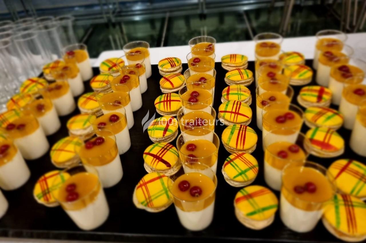 Plateau de desserts composés de verrines à deux couches et de tartelettes décorées de motifs colorés et cerises.