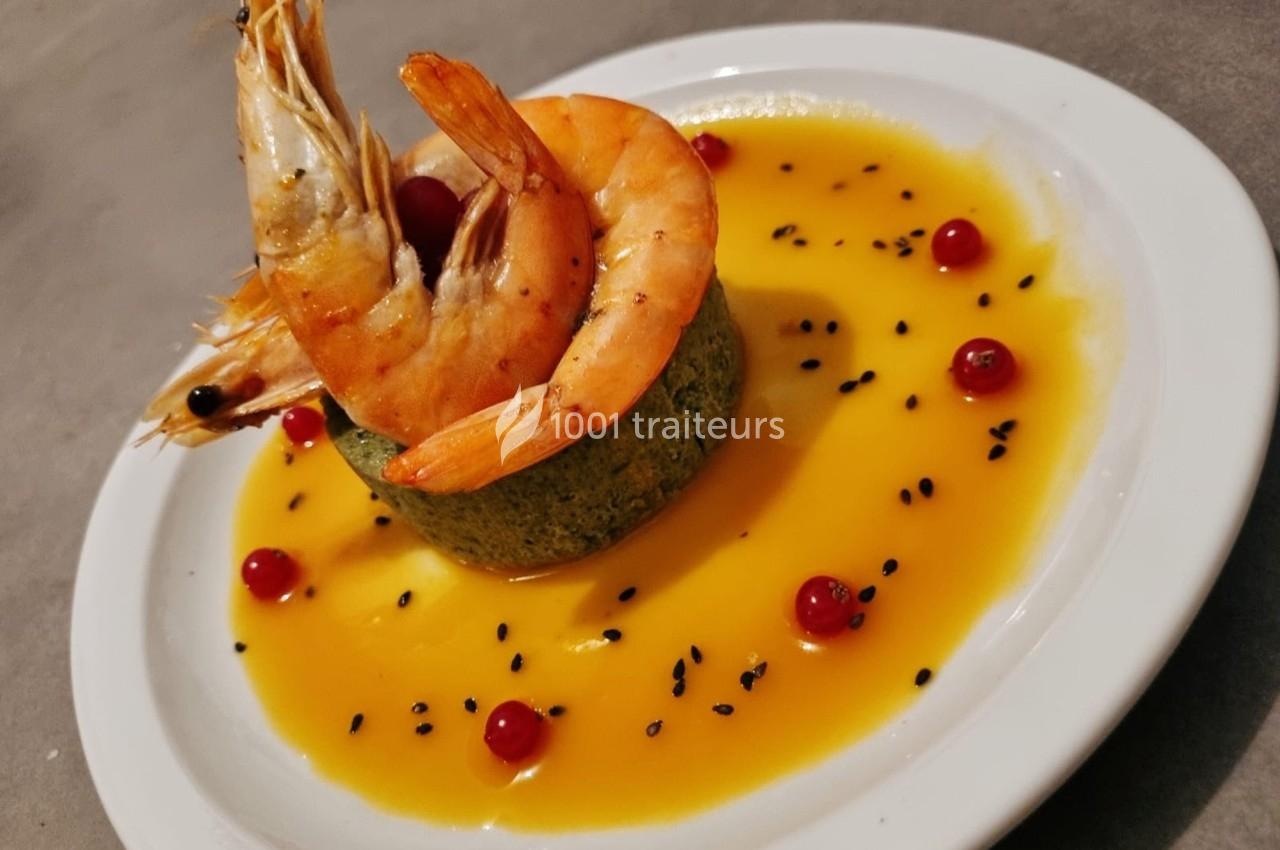Assiette avec crevettes sur un flan vert, nappée de sauce jaune, décorée de groseilles et graines noires.