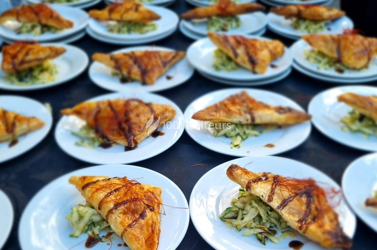Assiettes garnies de feuilletés dorés accompagnés de légumes râpés et décorés de sauce.