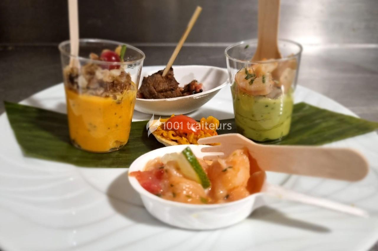 Assortiment de verrines et bouchées apéritives colorées, présentées sur une assiette blanche avec une feuille décorative.