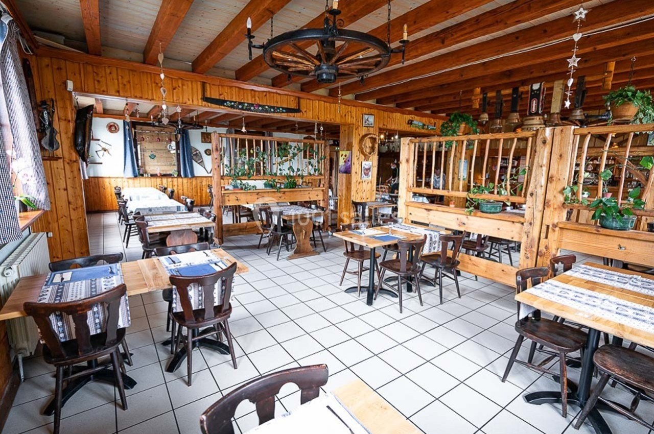 Salle de restaurant rustique avec mobilier en bois, décoration traditionnelle et lumière naturelle.