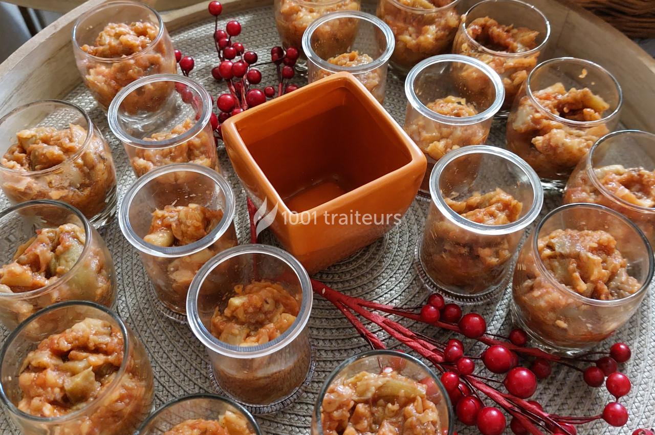 Verrines remplies d'une préparation à base de légumes, disposées autour d'un récipient orange sur un plateau décoré de baies…