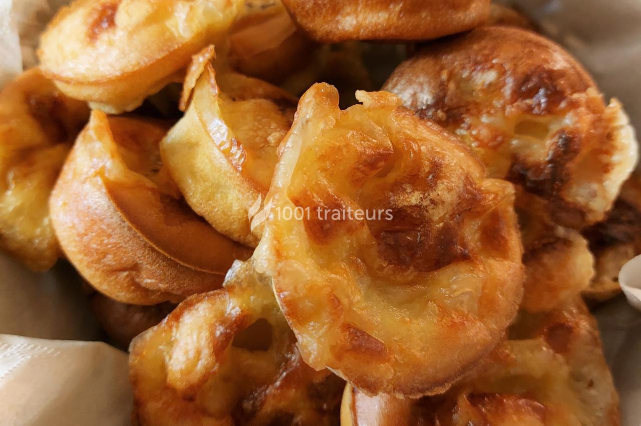 Assortiment de petits gougères dorés et croustillants, disposés dans un panier en tissu clair.