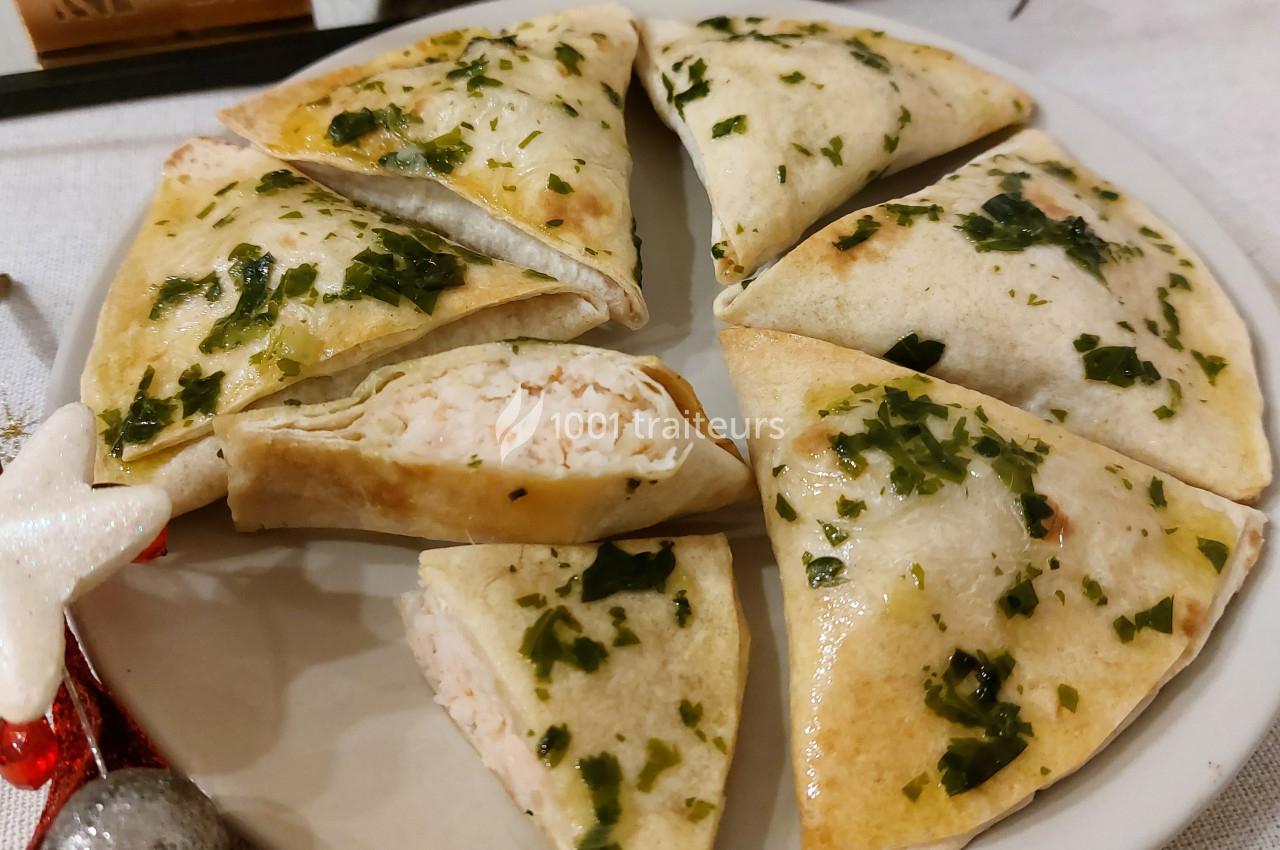 Assiette de triangles de pâte dorés garnis d'une farce crémeuse, parsemés de persil haché.