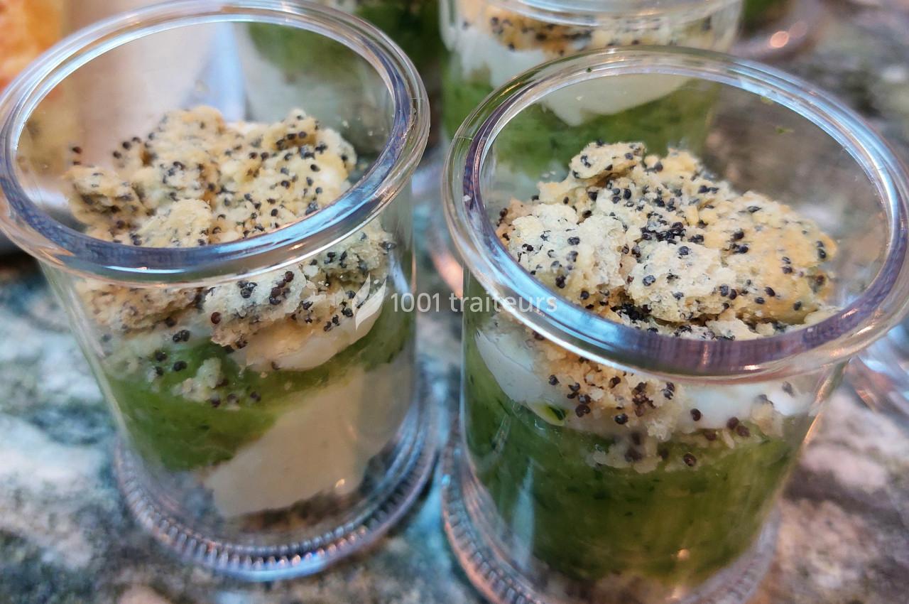 Verrines composées de purée verte, morceaux de poisson et crumble aux graines de pavot, présentées sur une table.