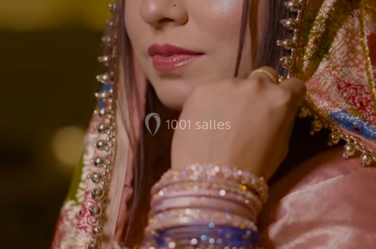 Femme portant une tenue traditionnelle ornée, avec un voile coloré et des bijoux, regardant vers l'objectif.