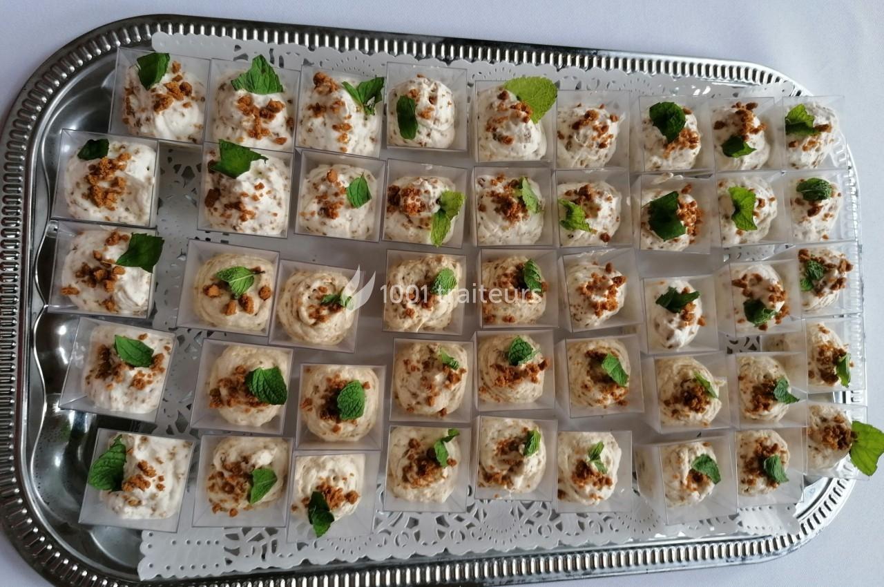 Plateau en métal contenant des verrines de mousse garnies de miettes de noix et de feuilles de menthe.