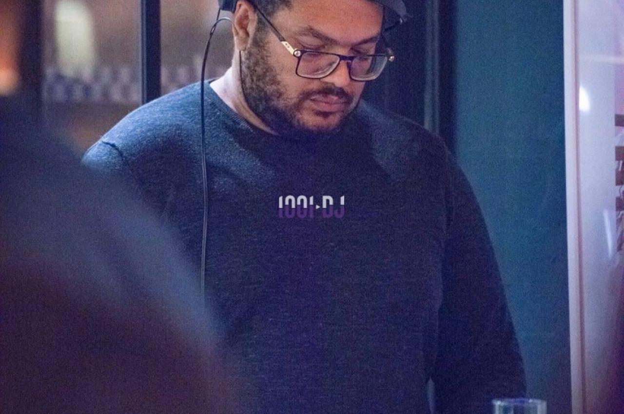 Un homme portant un casque audio se tient concentré devant un équipement, dans un environnement intérieur sombre.