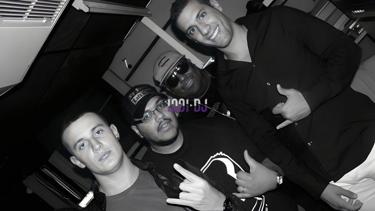 Quatre hommes posent ensemble dans un environnement intérieur, certains font des gestes de la main.