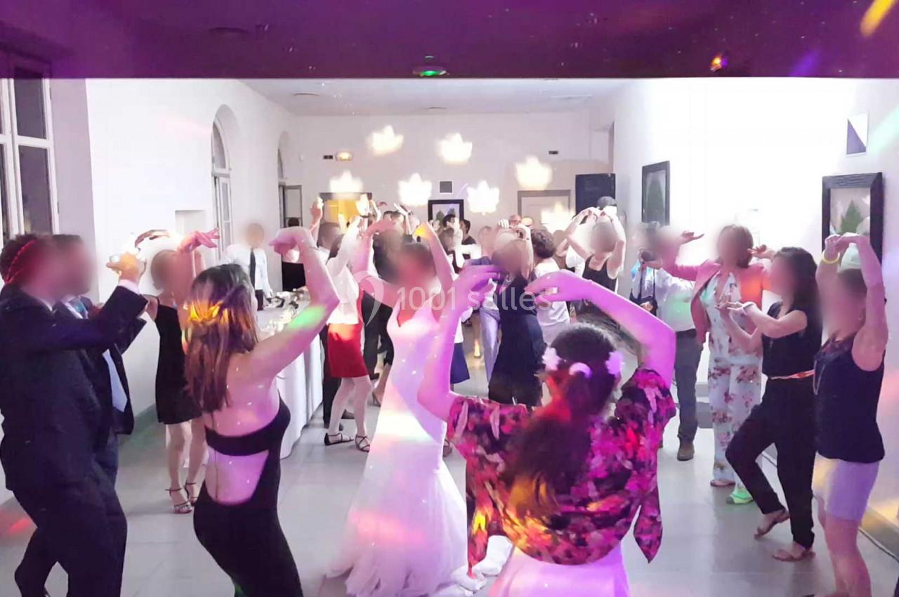 Personnes dansant dans une salle éclairée par des lumières colorées lors d'une fête ou d'un événement festif.