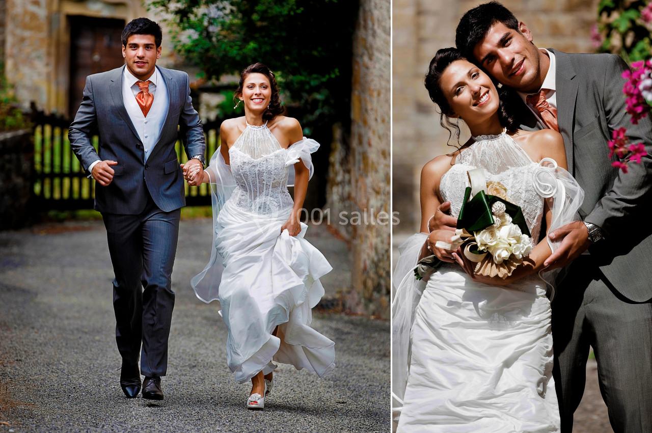 Un couple en tenue de mariage, souriant et posant à l'extérieur dans un cadre verdoyant et pavé.