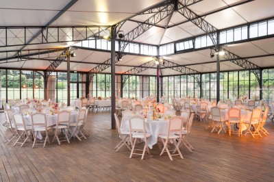 Façade d'un château en pierre et briques entouré d'une pelouse et d'arbres sous un ciel bleu clair.