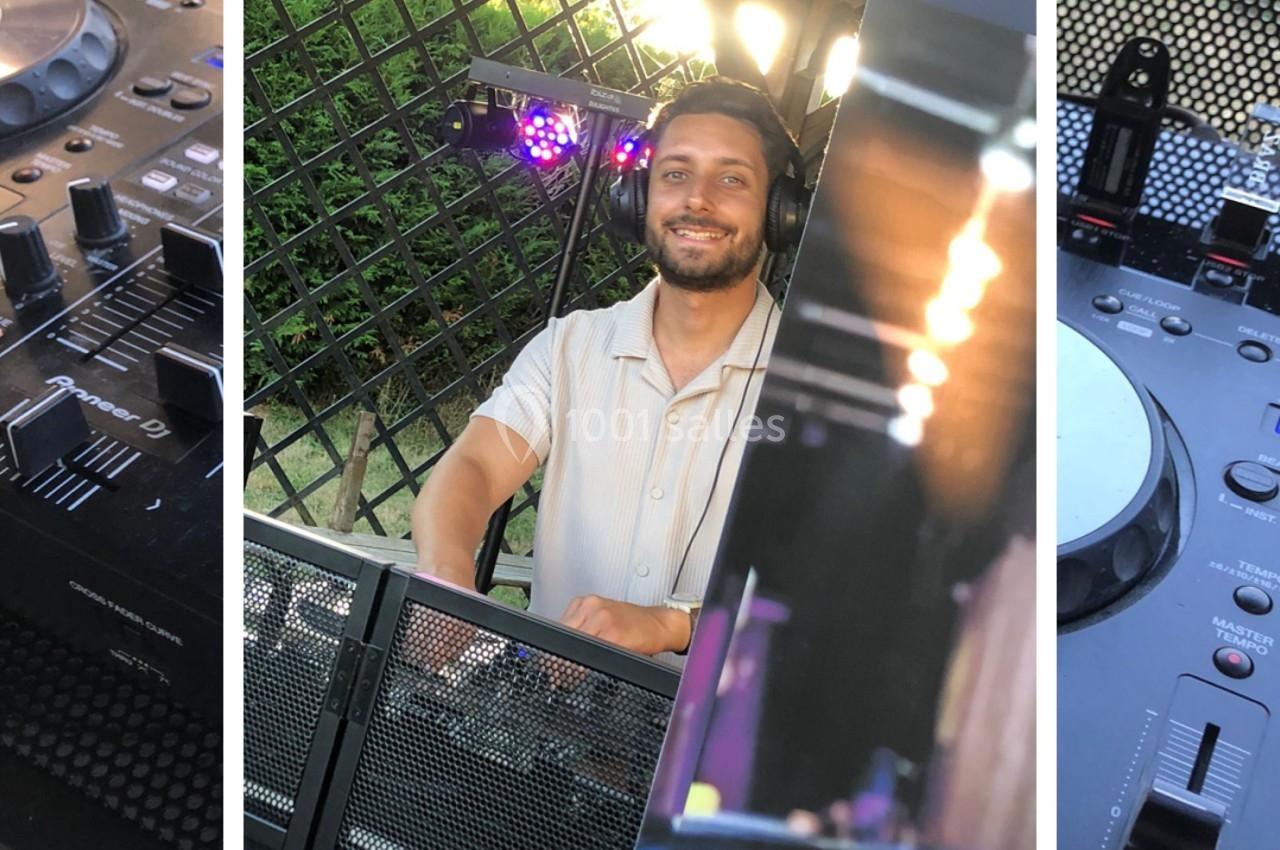 Un homme souriant se tient derrière une table de mixage avec des lumières et une grille en arrière-plan.