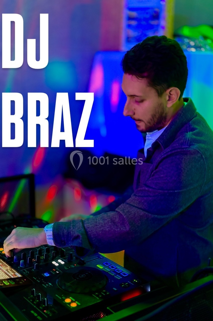 Un DJ mixe de la musique sur une table de mixage dans un environnement éclairé par des lumières colorées.