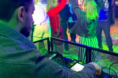 Miniature DJ La Queue-les-Yvelines (Yvelines) - DJ Braz #22 Main ajustant les réglages sur une table de mixage DJ illuminée par des lumières colorées.