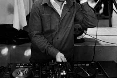 Miniature DJ La Queue-les-Yvelines (Yvelines) - DJ Braz #26 Main ajustant des réglages sur une table de mixage DJ lumineuse avec des écrans et des boutons colorés.